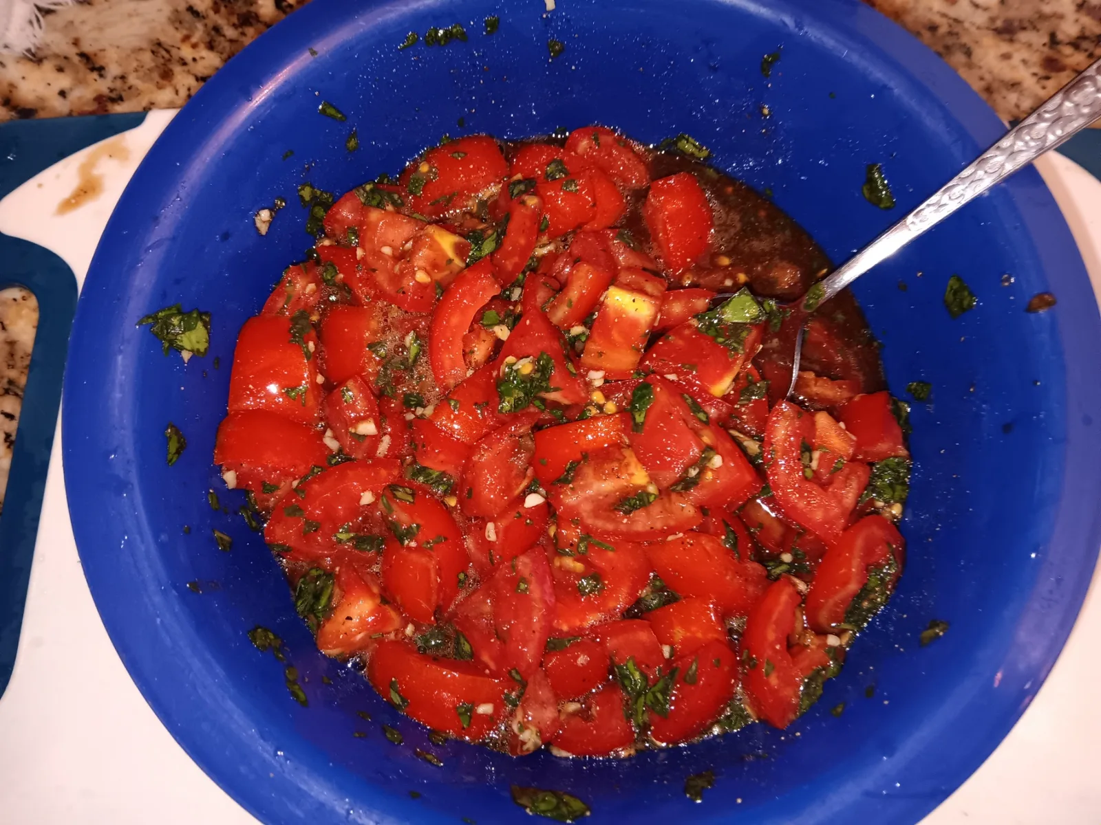 Finished tomato bruschetta mixture with basil and garlic in a blue bowl